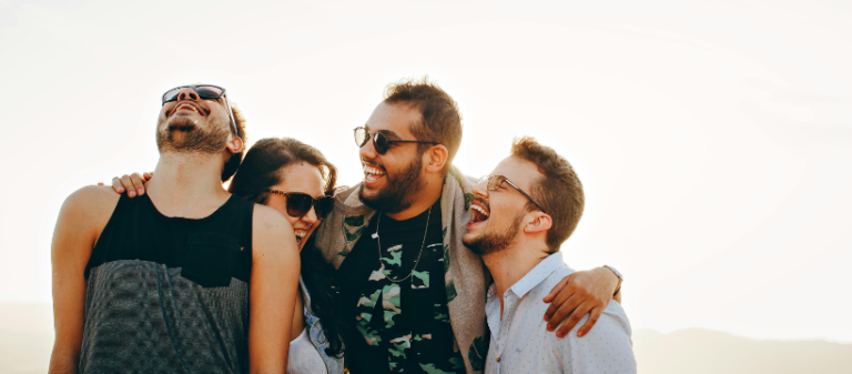 Group of diverse friends smiling and looking happy together – representing the benefits of a holistic approach to health, wellbeing, and balanced living