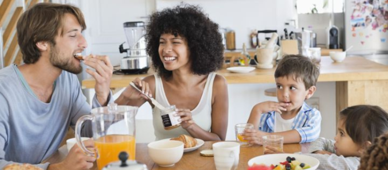 Family smiling and enjoying breakfast together at the table – representing the importance of a healthy morning meal for energy, wellbeing, and long-term health